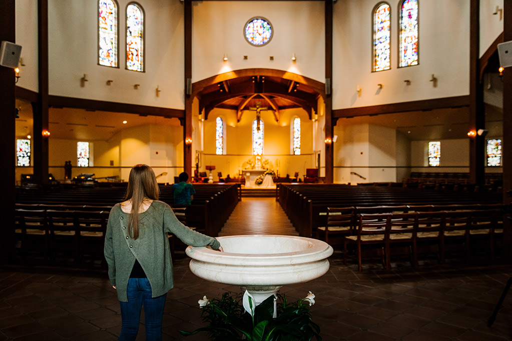 Student with hand in holy water bowl staring into the chapel