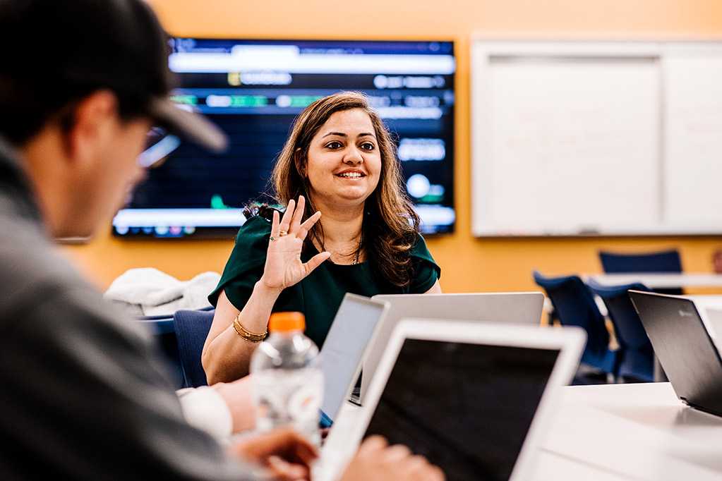 Professor teaching class with student staring at computer