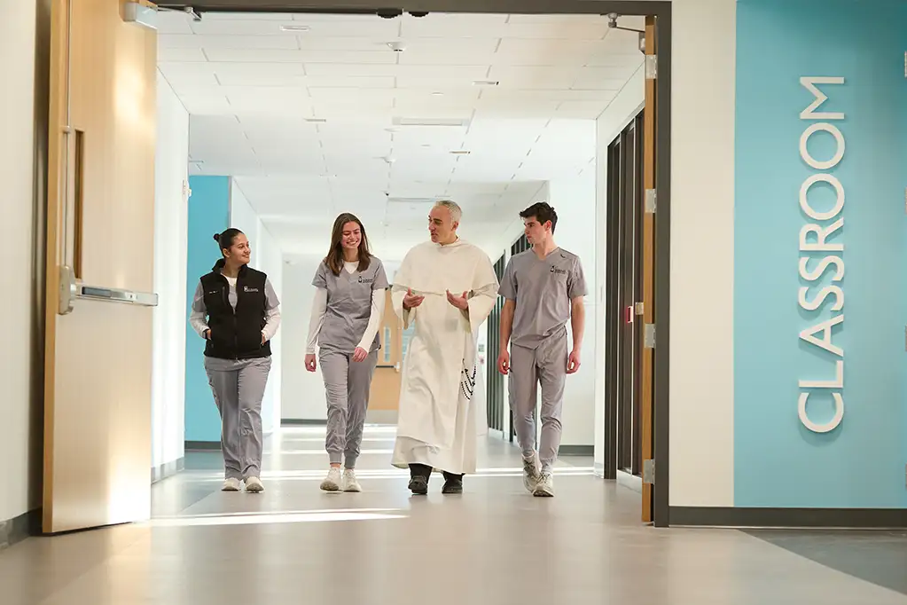 students and a priest walking in the new Mondor center