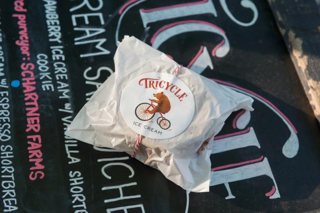 Wrapped ice cream sandwich by alumni owned Tricycle placed on a chalkboard menu