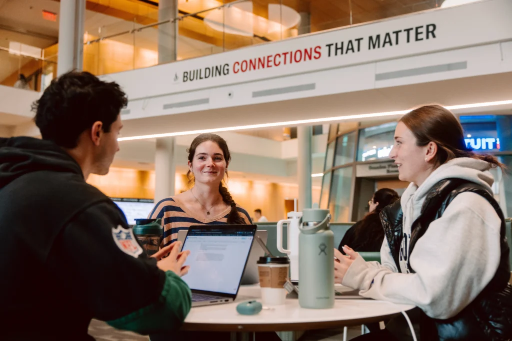 Three students sitting at a table, working and talking