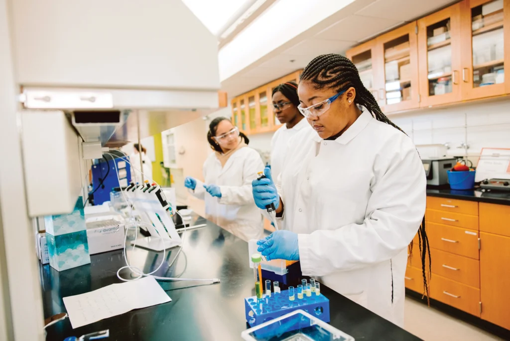 Three students wearing safety equipment and working in a lab