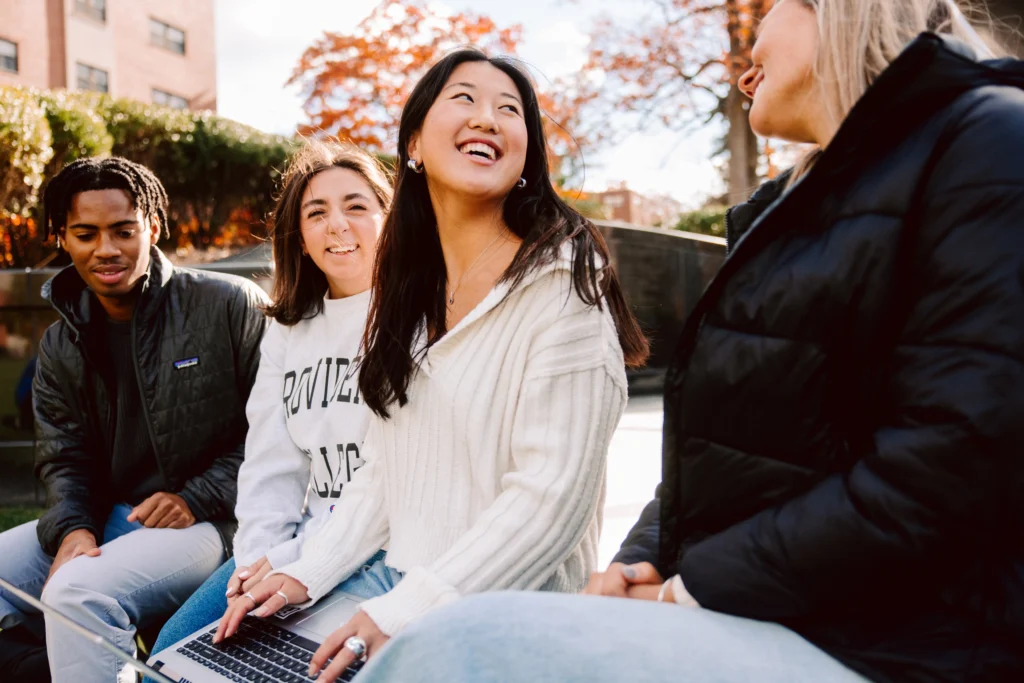 Group of students laughing and talking while sitting in the Calabria Plaza